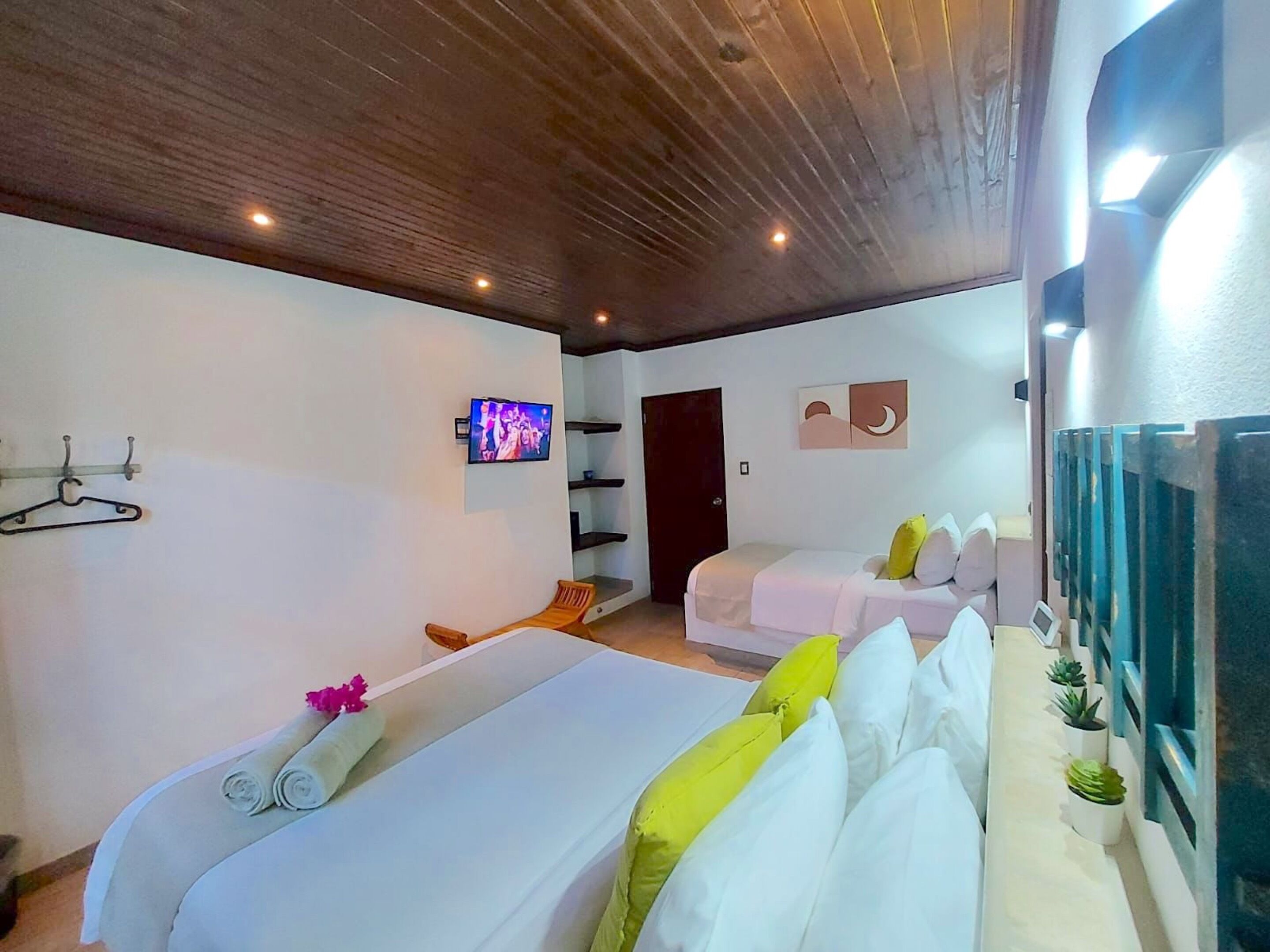 Une chambre d’hôtel avec deux lits, une télévision, un plafond en bois et une porte.