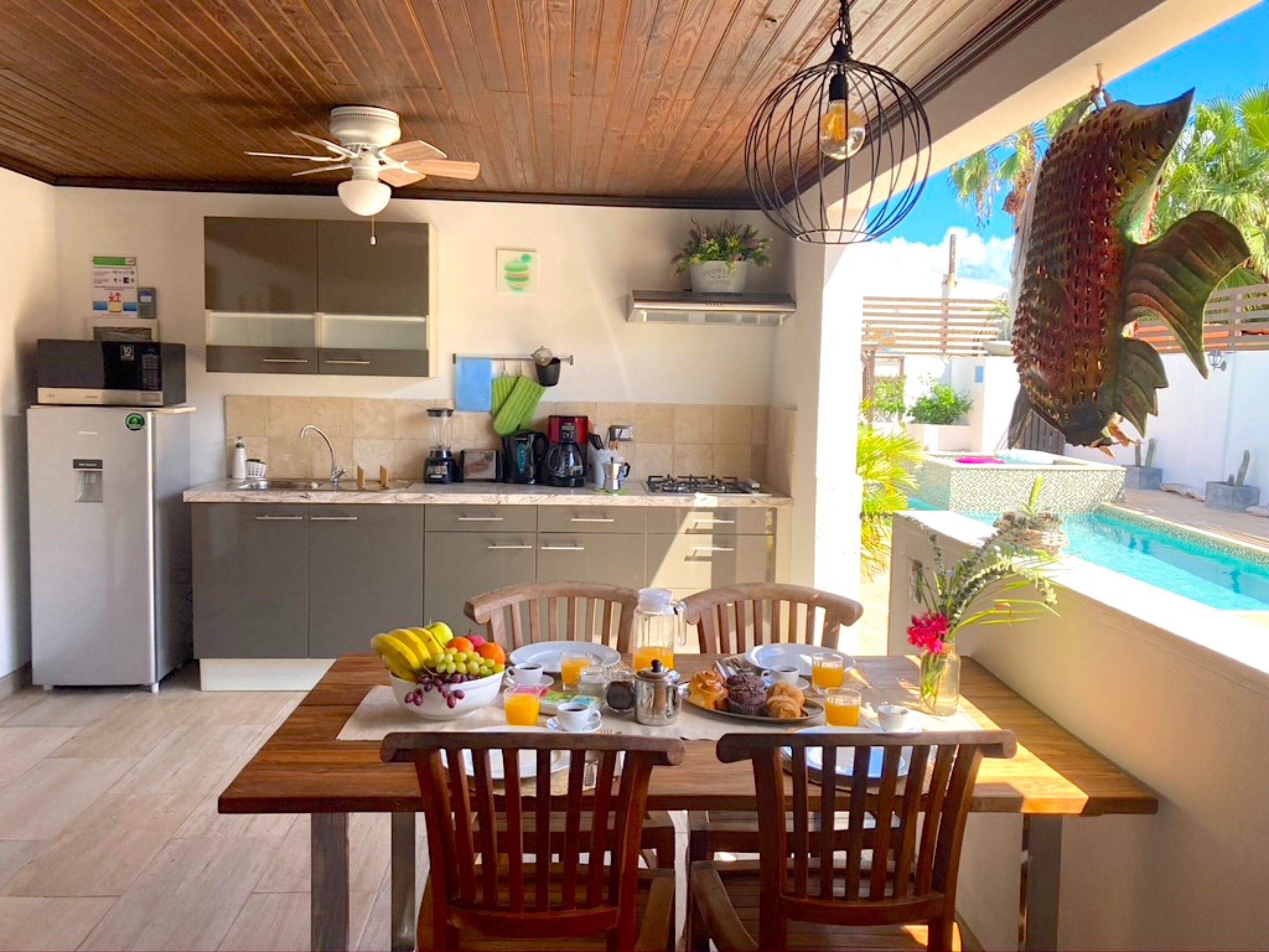 Une cuisine moderne avec un coin repas, une piscine et une vue sur l’extérieur.