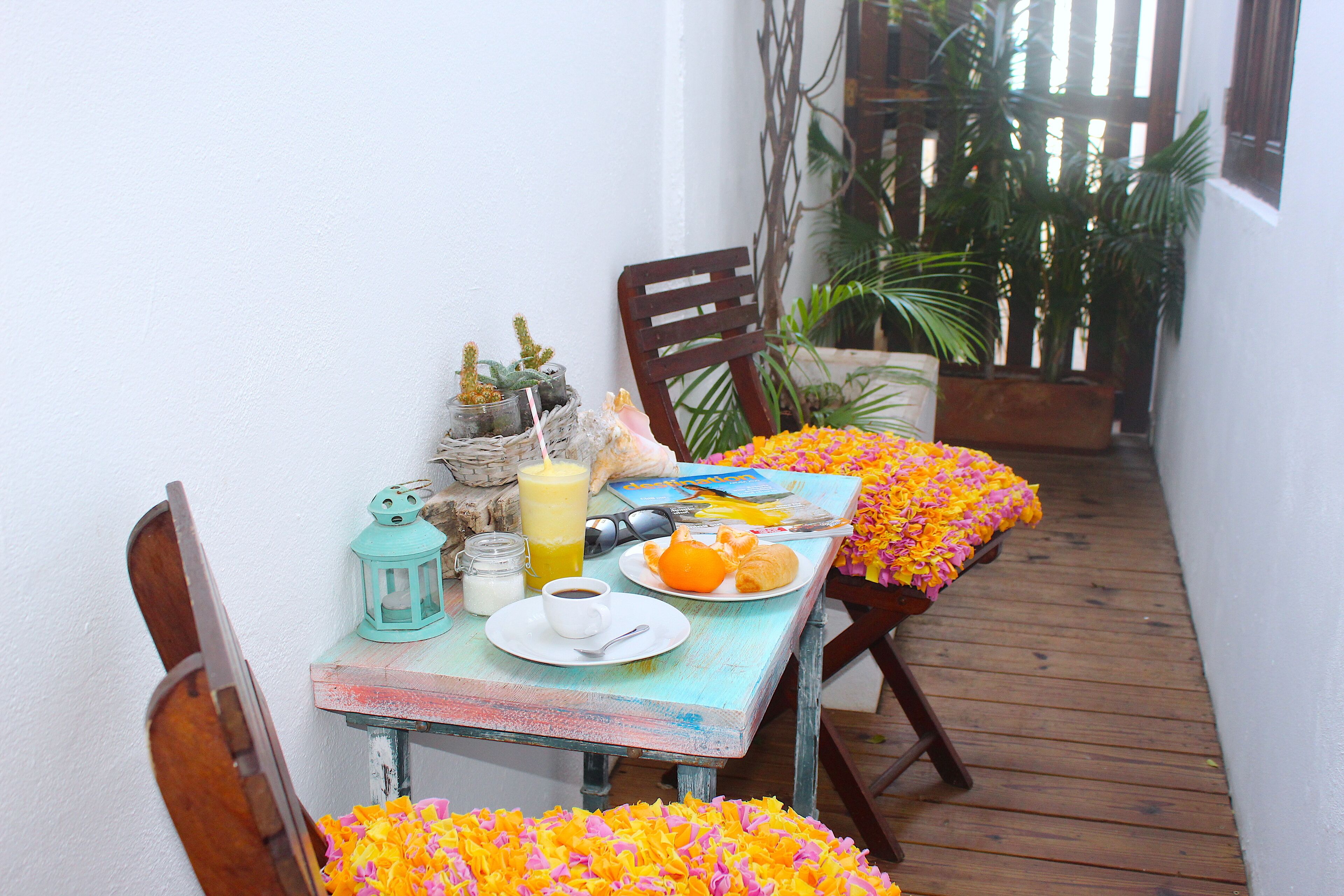 A small dining area with a table set for breakfast, including a plate of orange slices, a cup of coffee, and a glass of orange juice.
