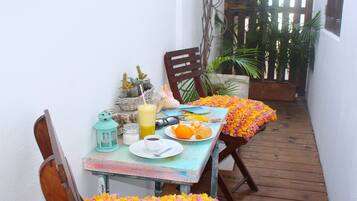 A small dining area with a table set for breakfast, including a plate of orange slices, a cup of coffee, and a glass of orange juice.