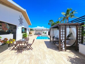 A pool area with a pergola, outdoor seating, and a view of the pool.