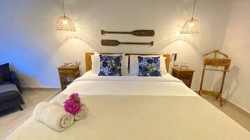 Una cama bien hecha con sábanas blancas, dos almohadas decorativas, un cabecero de madera y dos mesitas de noche con lámparas.