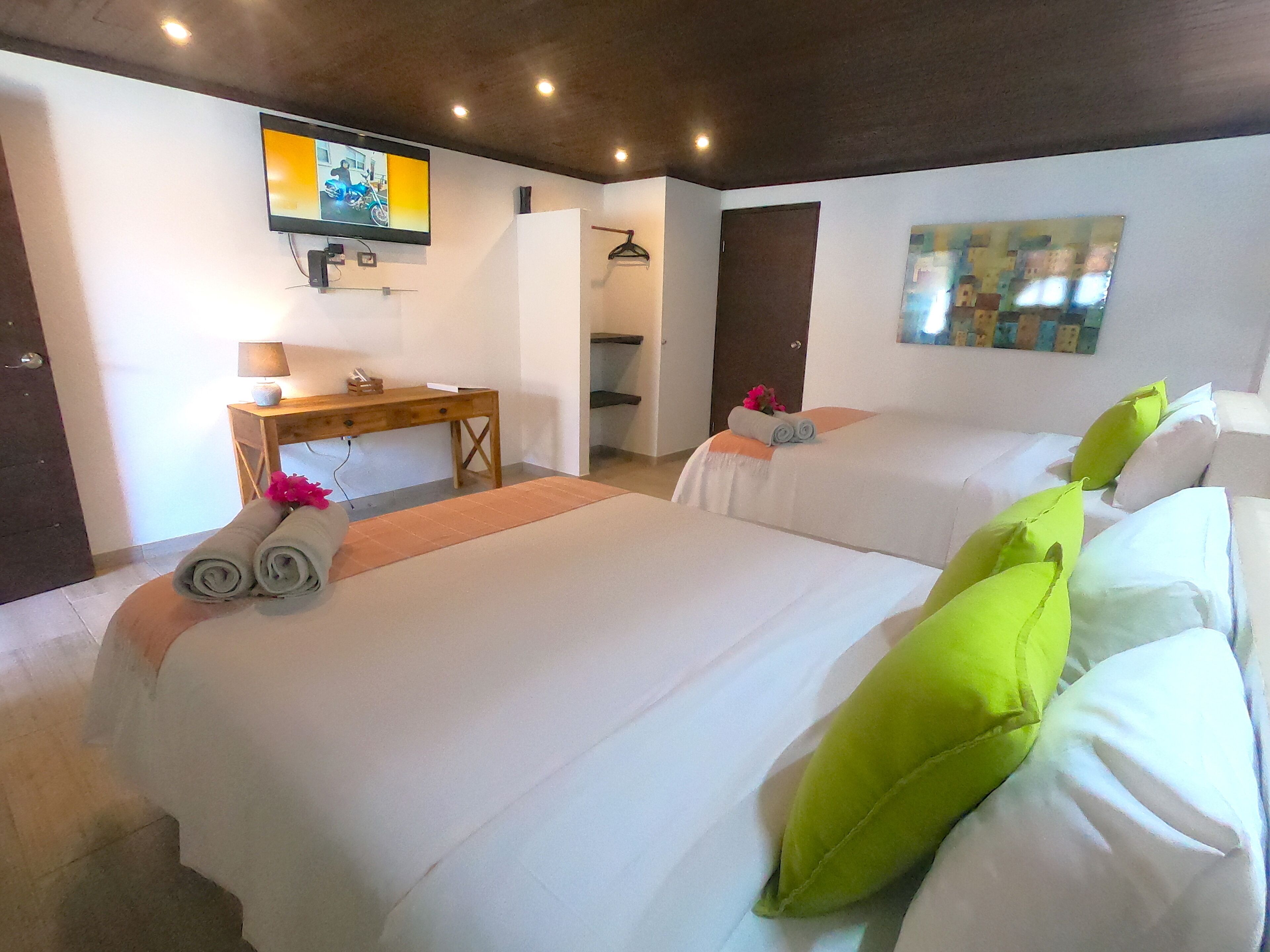 Habitación de hotel con dos camas, un escritorio, un televisor y un cuadro en la pared.