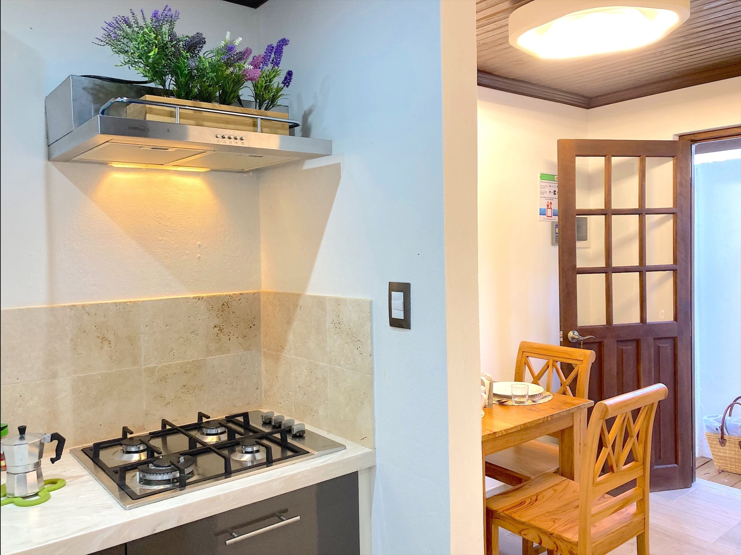 A kitchen with a gas stove, a built-in oven, and a wall-mounted shelf with flowers.