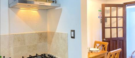 A kitchen with a gas stove, a built-in oven, and a wall-mounted shelf with flowers.