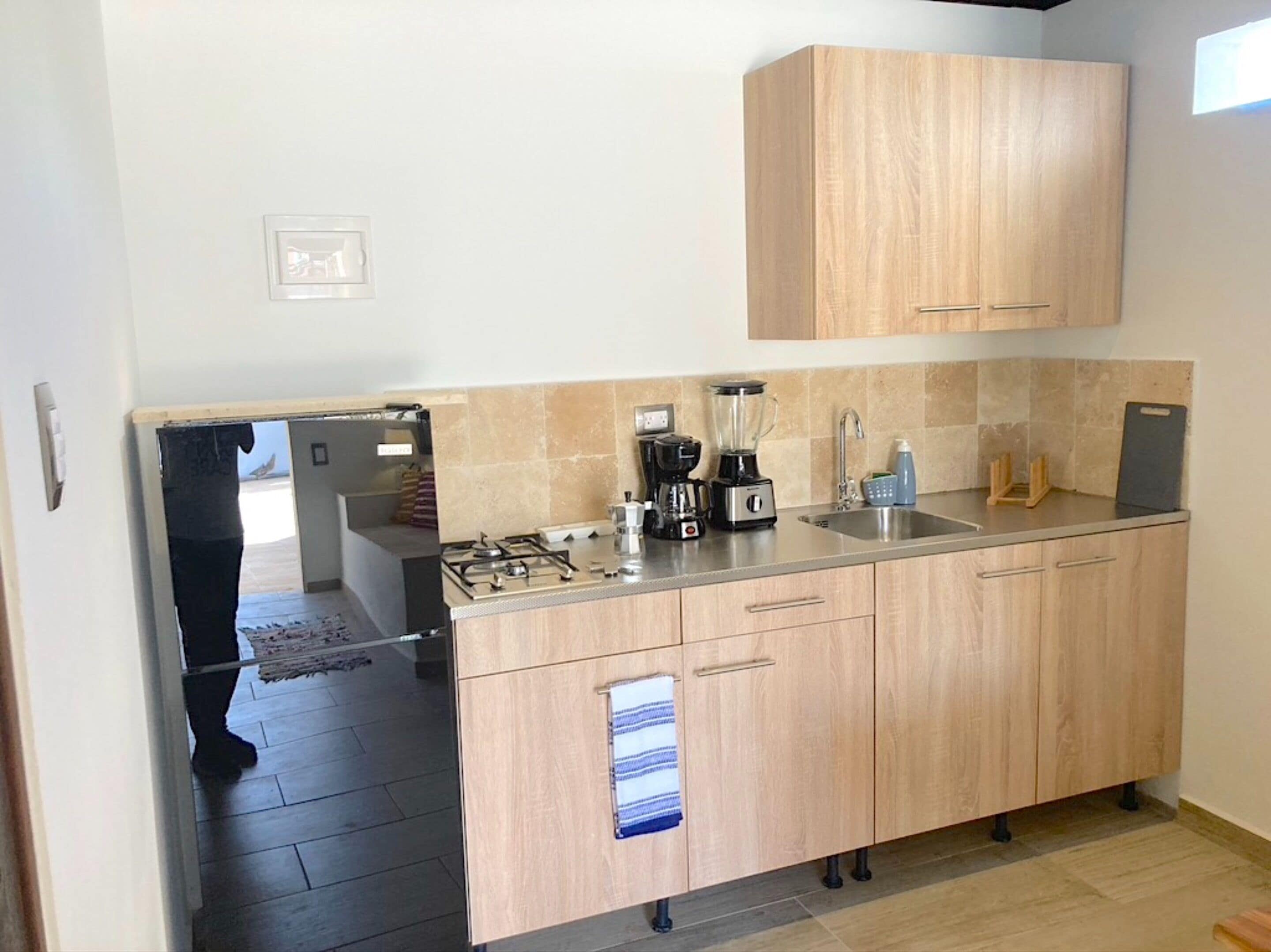 A modern kitchen with wooden cabinets, a gas stove, a coffee maker, and a sink.