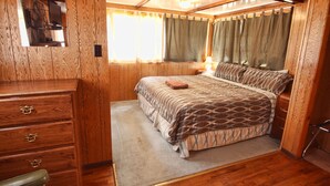 A wooden-paneled bedroom with a bed, dresser, and mirror. - Tiny Town Cabins (Estes Park)