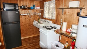 A compact kitchen with a black refrigerator, white stove, and microwave. - Tiny Town Cabins (Estes Park)
