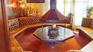 A cozy living room with a fireplace, leather seating, and a flat-screen TV on the wall. - Hotel Het Galjoen (Dronten)