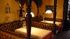 A traditional inn with leather booth seating and wooden beams. Tables are set with white tablecloths and red napkins. - Hotel Het Galjoen (Dronten)