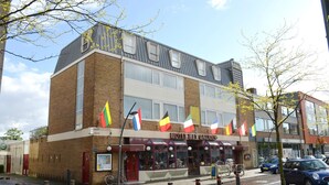 A hotel with multiple flags, a cafe, and a bicycle parked outside. - Hotel Het Galjoen (Dronten)