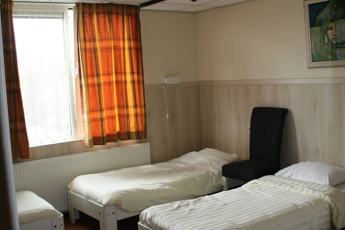A room with two single beds, a chair, and a radiator.