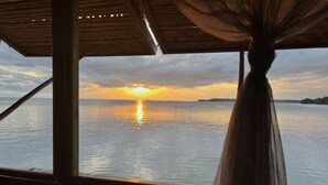 Uitzicht vanuit een overdekt gebied op kalm water bij zonsondergang.