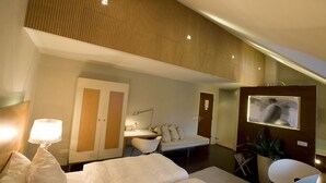 A modern hotel room with a bed, a desk, a chair, a wardrobe, and a television. - Droste's herberg (Tubbergen)