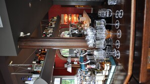 A bar area with a wooden counter, multiple glassware, and a view of the restaurant in the background. - Droste's herberg (Tubbergen)