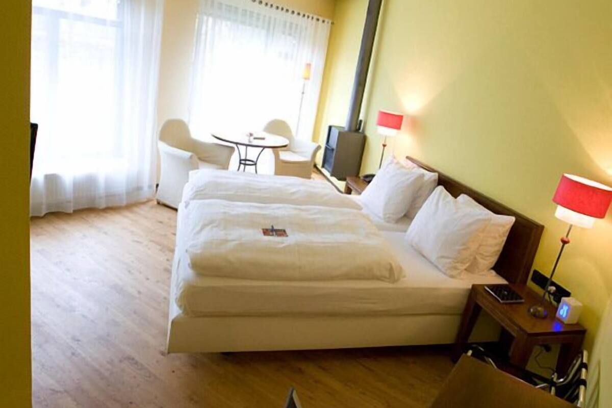 Una habitación de hotel con cama, escritorio, silla, televisor y lámpara.