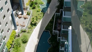 Um edifício residencial alto com várias varandas, um caminho central e área de piscina.