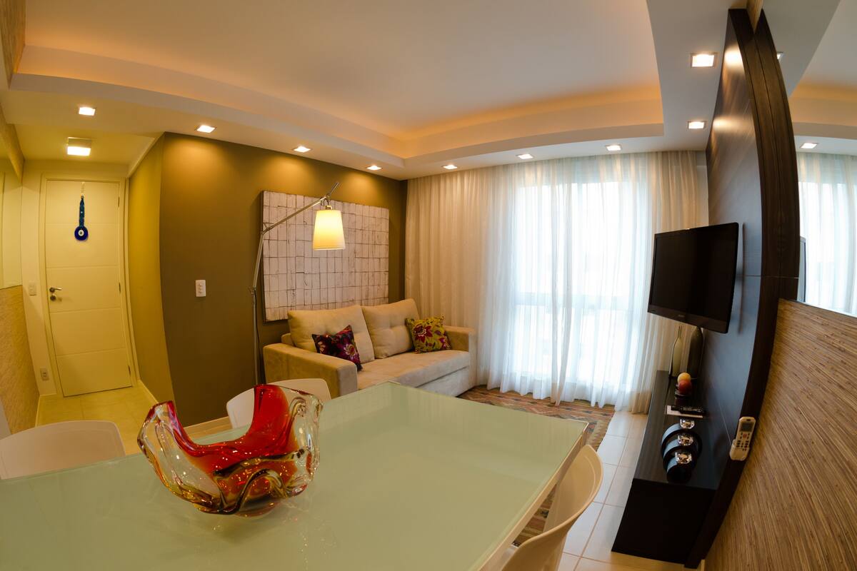 Una sala de estar moderna con un sofá, una mesa de centro de vidrio y un televisor de pantalla plana montado en la pared.