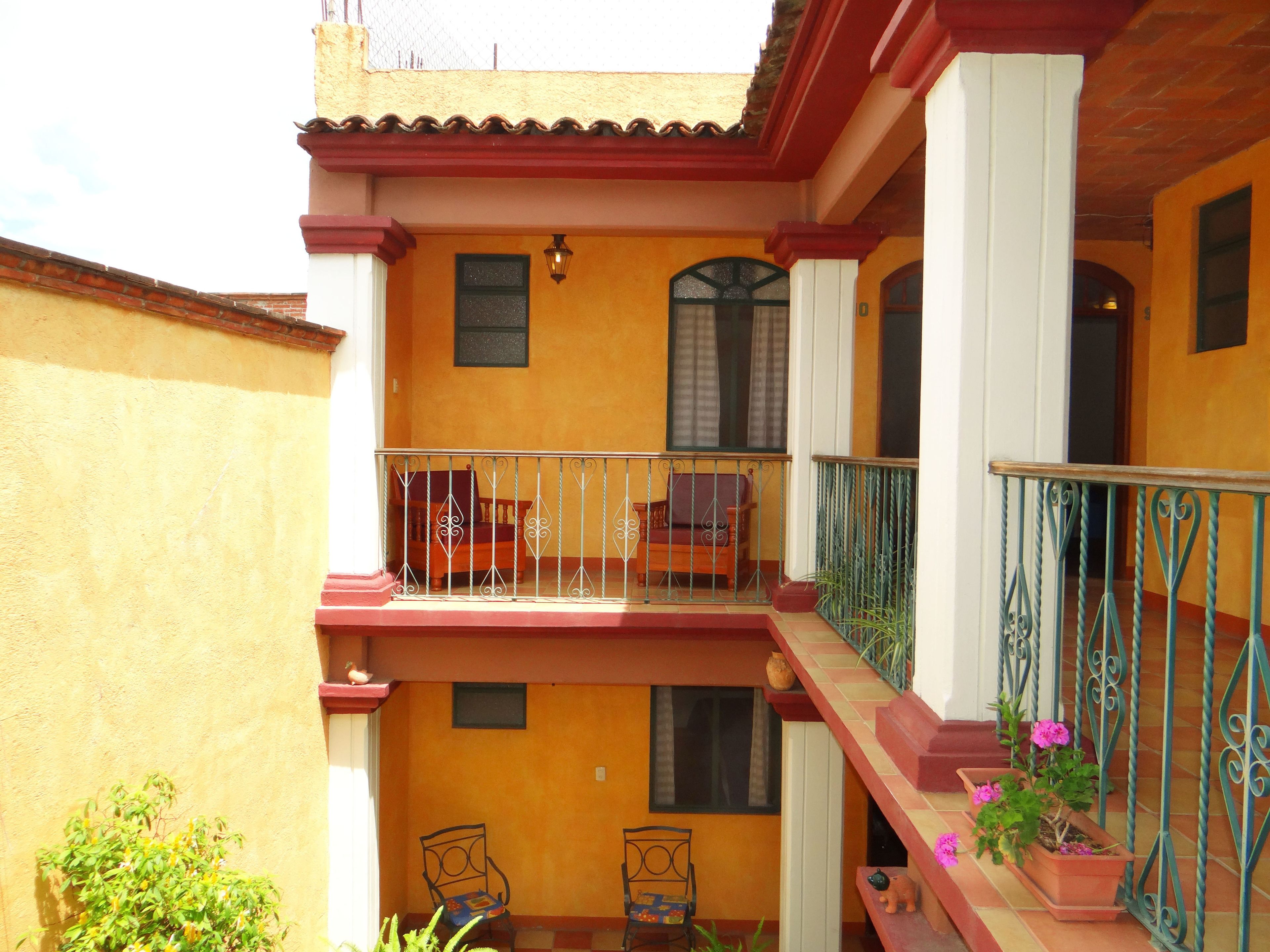 A two-story building with a balcony, a small table, and chairs.