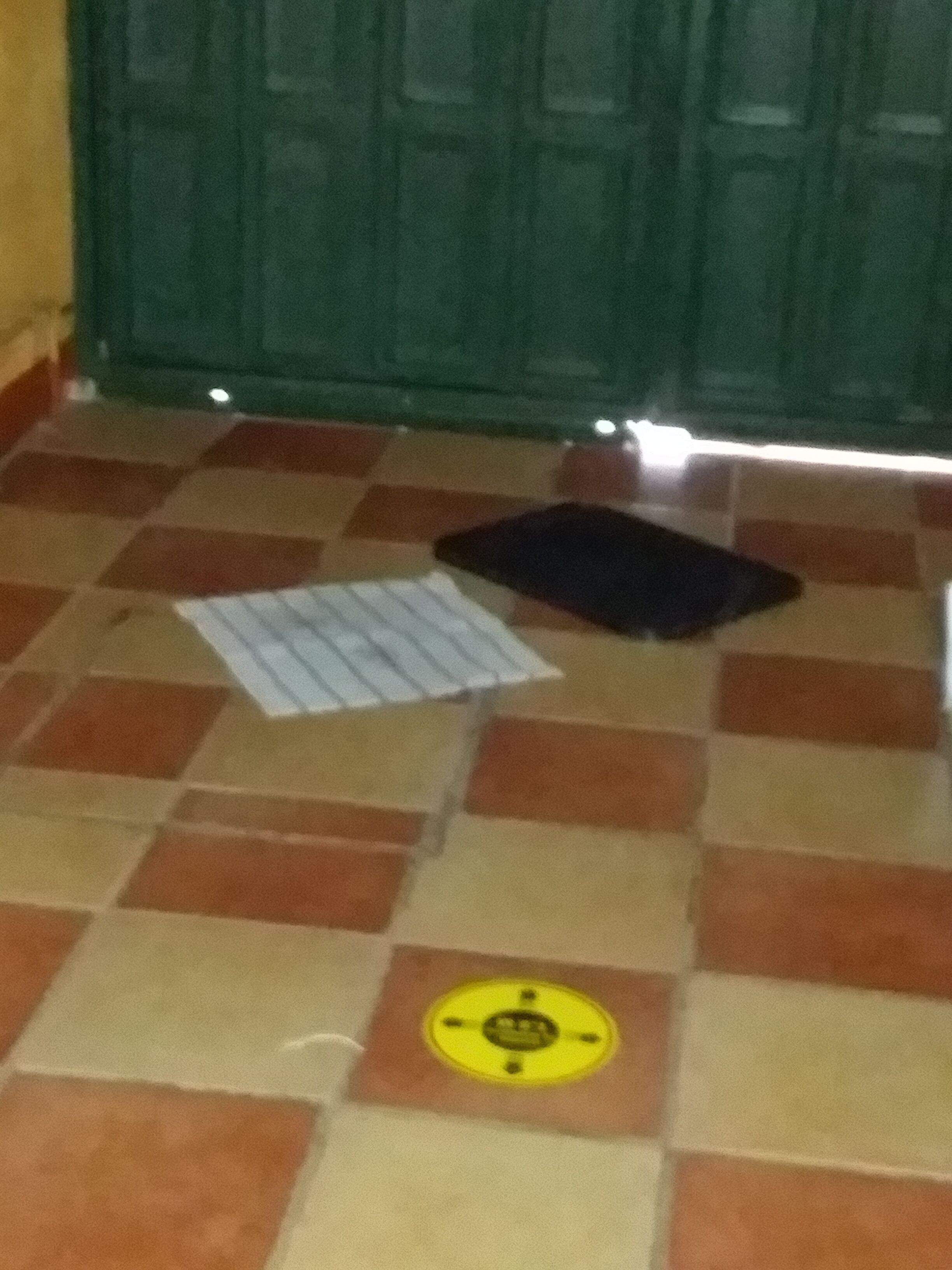 A tiled floor with a checkered pattern, a yellow circular feature, and a black object.