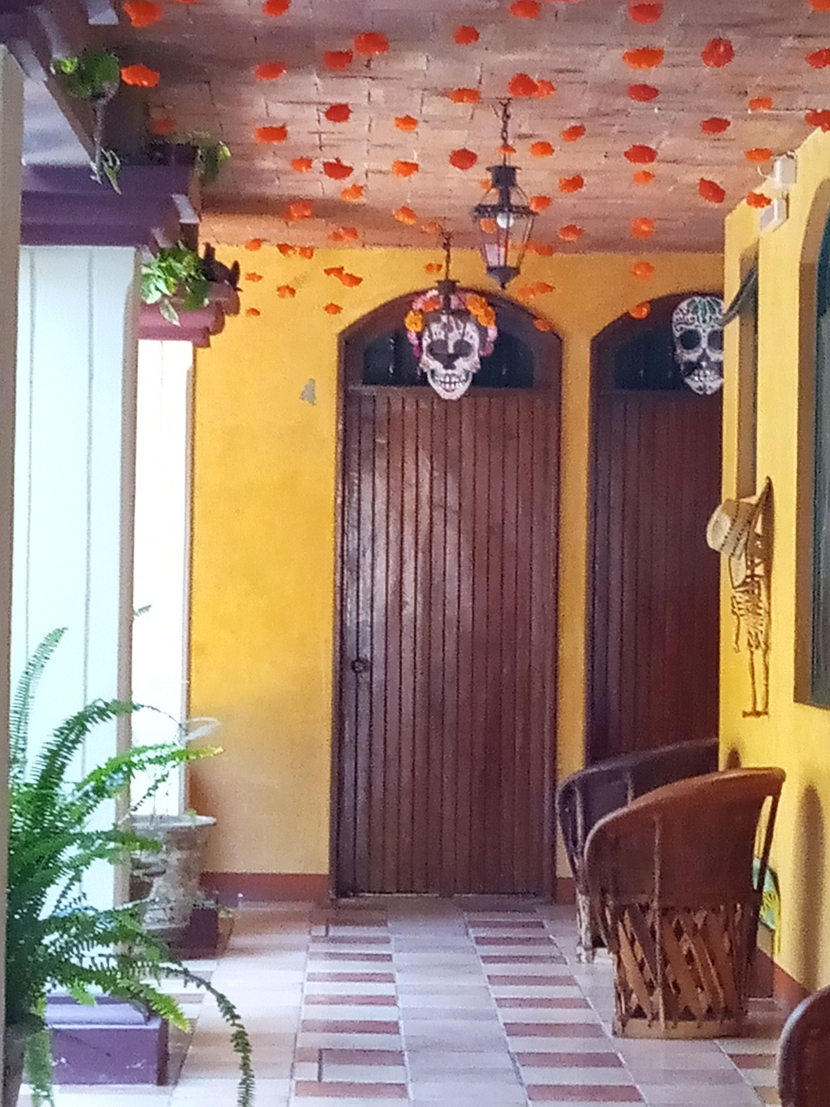 A hallway with a tiled floor, a wooden door, and a skeleton decoration on the wall.