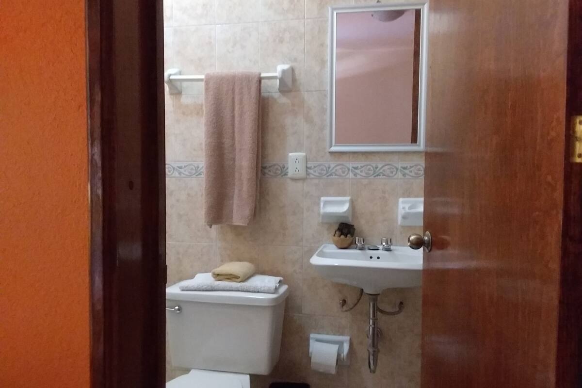 Et badeværelse med toilet, vask og håndklædestang med et håndklæde.