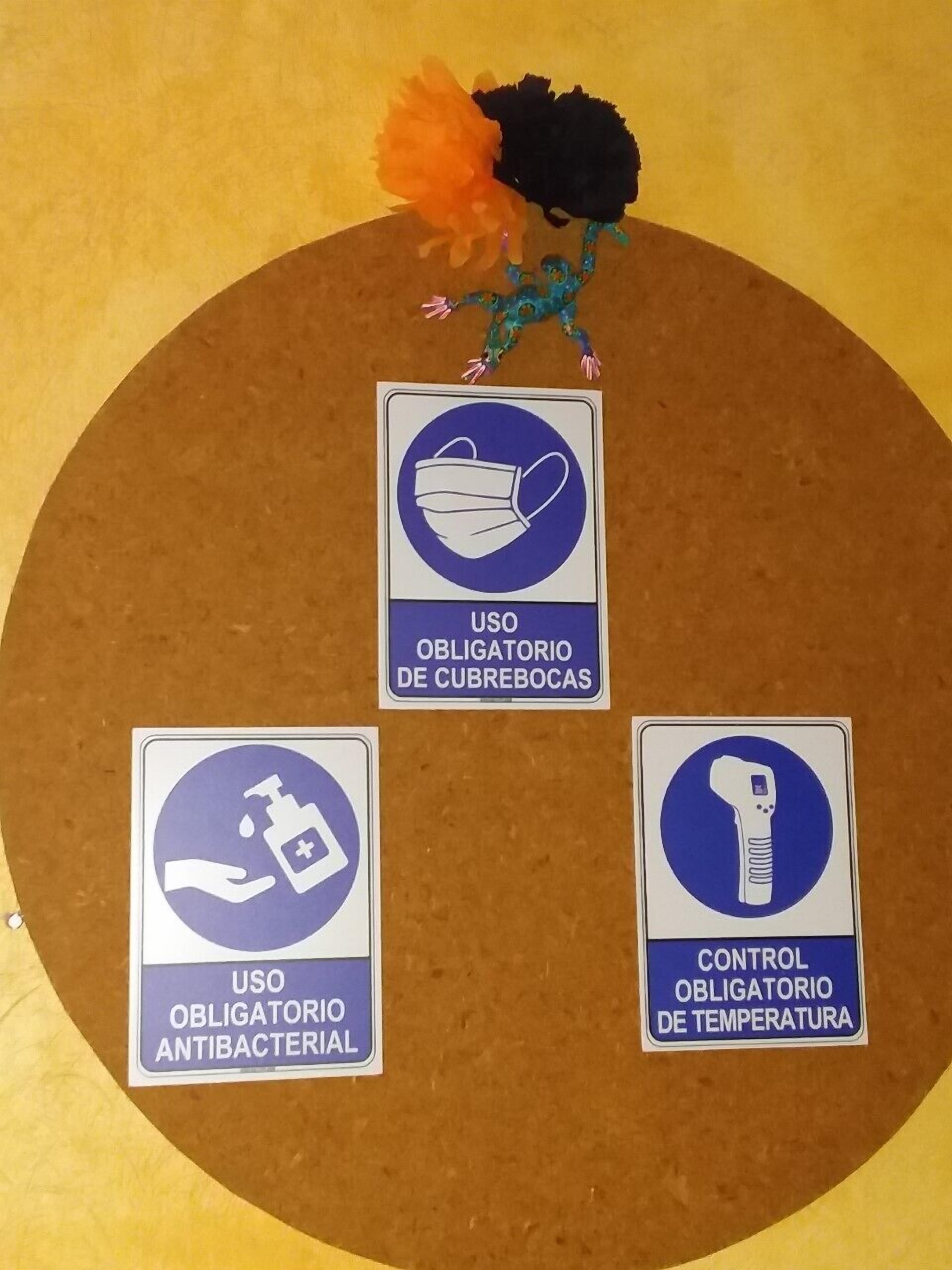 Un panneau d’affichage en liège avec trois affiches relatives à l’hygiène et à la sécurité : port du masque, utilisation d’un gel hydroalcoolique et contrôle de la température.
