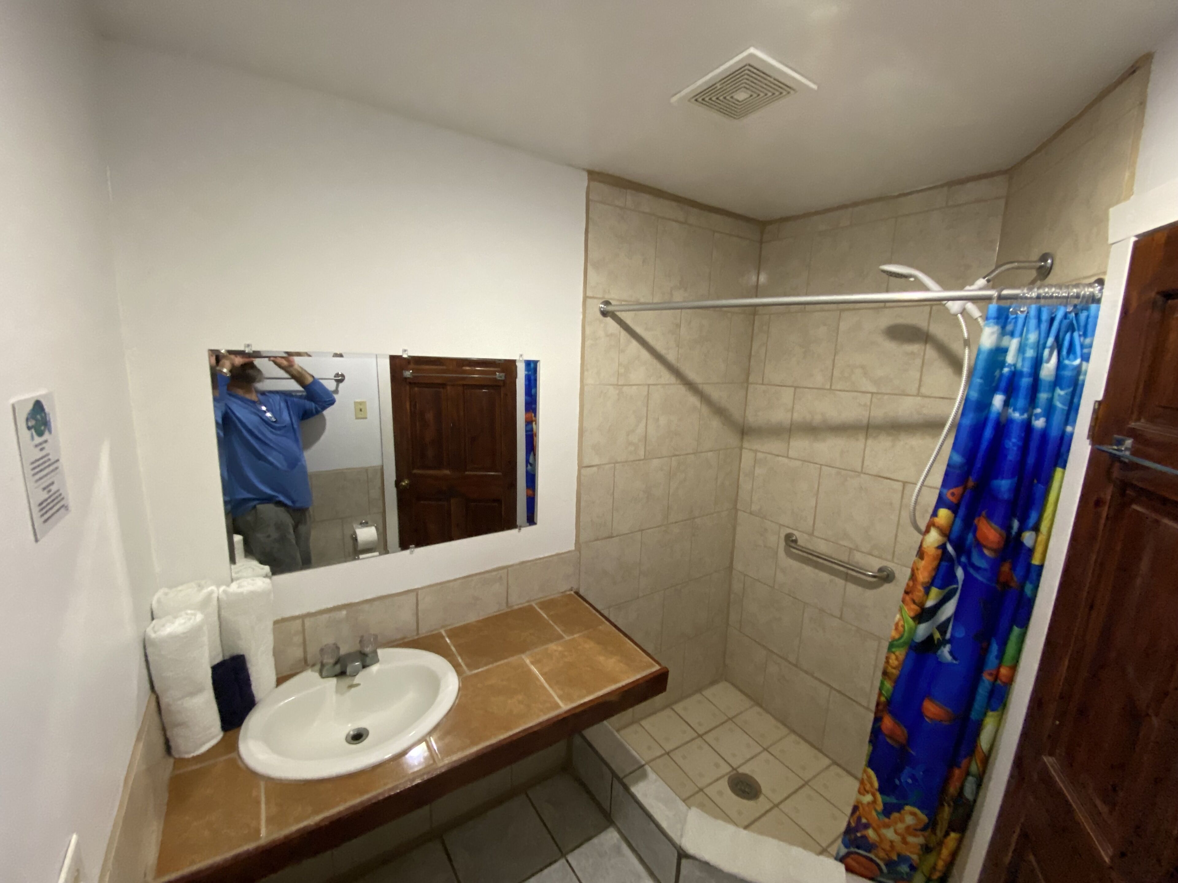Un baño con lavamanos, espejo, ducha y puerta.