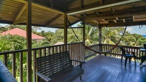 A wooden deck with a hammock, a bench, and two chairs. - Mariposa Lodge (Roatan)