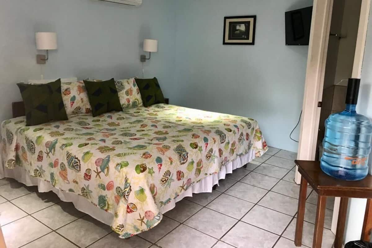 Ein Schlafzimmer mit einem Bett, zwei Wandleuchten, einem gerahmten Bild und einem Wasserspender.