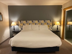 Une chambre d’hôtel avec un grand lit, deux lampes de chevet, un téléphone et une porte en verre.