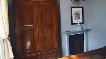Une pièce avec une grande armoire en bois, un tableau encadré au mur et une cheminée avec un manteau bleu.