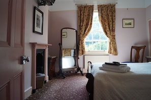 A bedroom with a bed, a mirror, a dresser, and a window with curtains.