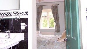 Ein Badezimmer mit einem schwarzen und weißen Marmorbecken, einem Chandelier und einem Fenster mit Vorhängen.