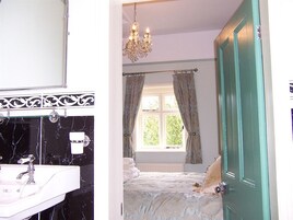 Um banheiro com pia de mármore preto e branco, um lustre e uma janela com cortinas.