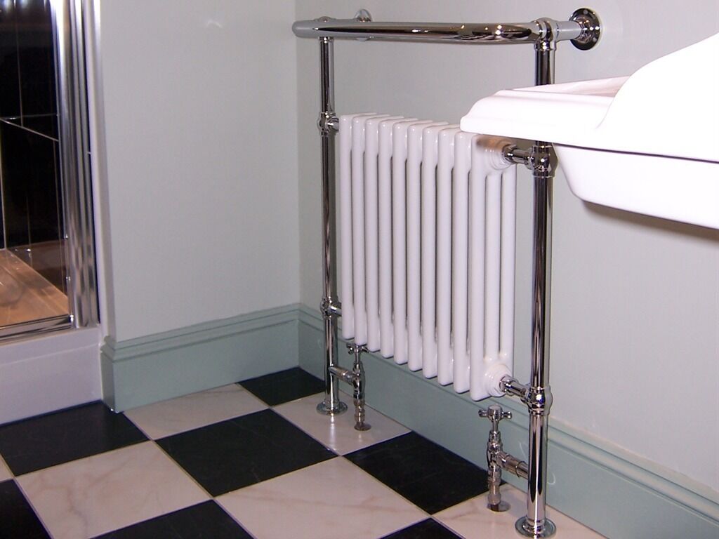 Une salle de bain avec un radiateur blanc, des robinetteries chromées et un carrelage à motifs géométriques.