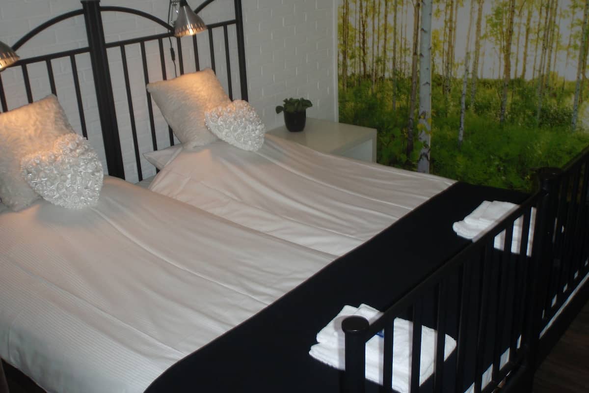 A bed with white linens, black metal headboard, and two bedside lamps.