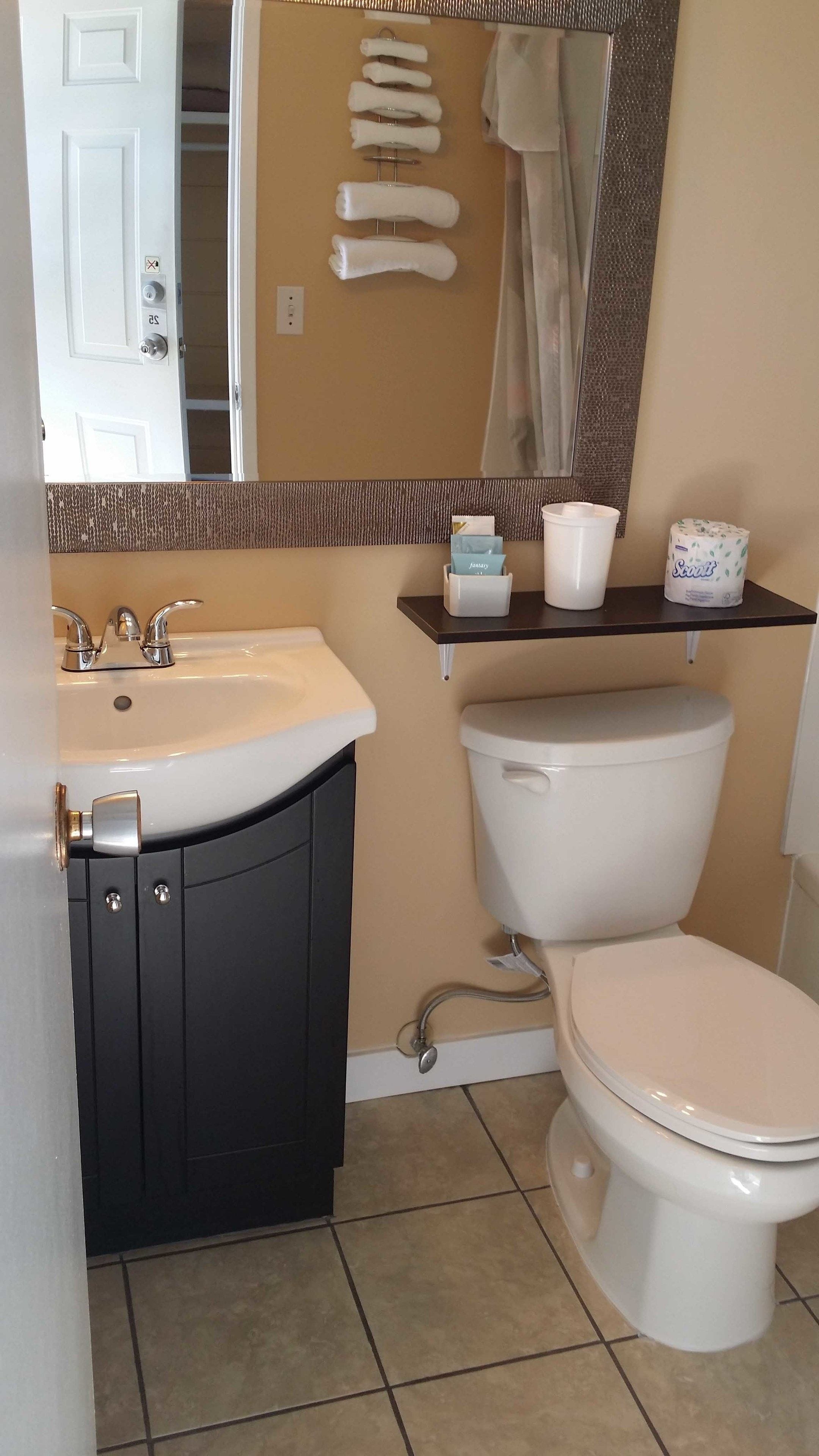 Un baño con lavamanos blanco, muebles negros, inodoro y espejo.