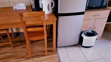 Una kitchenette equipada con cafetera, hervidor, microondas y refrigerador.