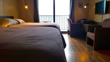 A hotel room with two beds, a desk, a chair, and a TV on the wall.