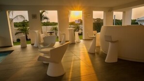 Ein moderner Außenbereich mit weißen Möbeln, einem Pool und Blick auf den Sonnenuntergang.