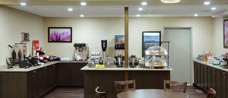 A hotel kitchen with a central island, seating area, and various appliances.