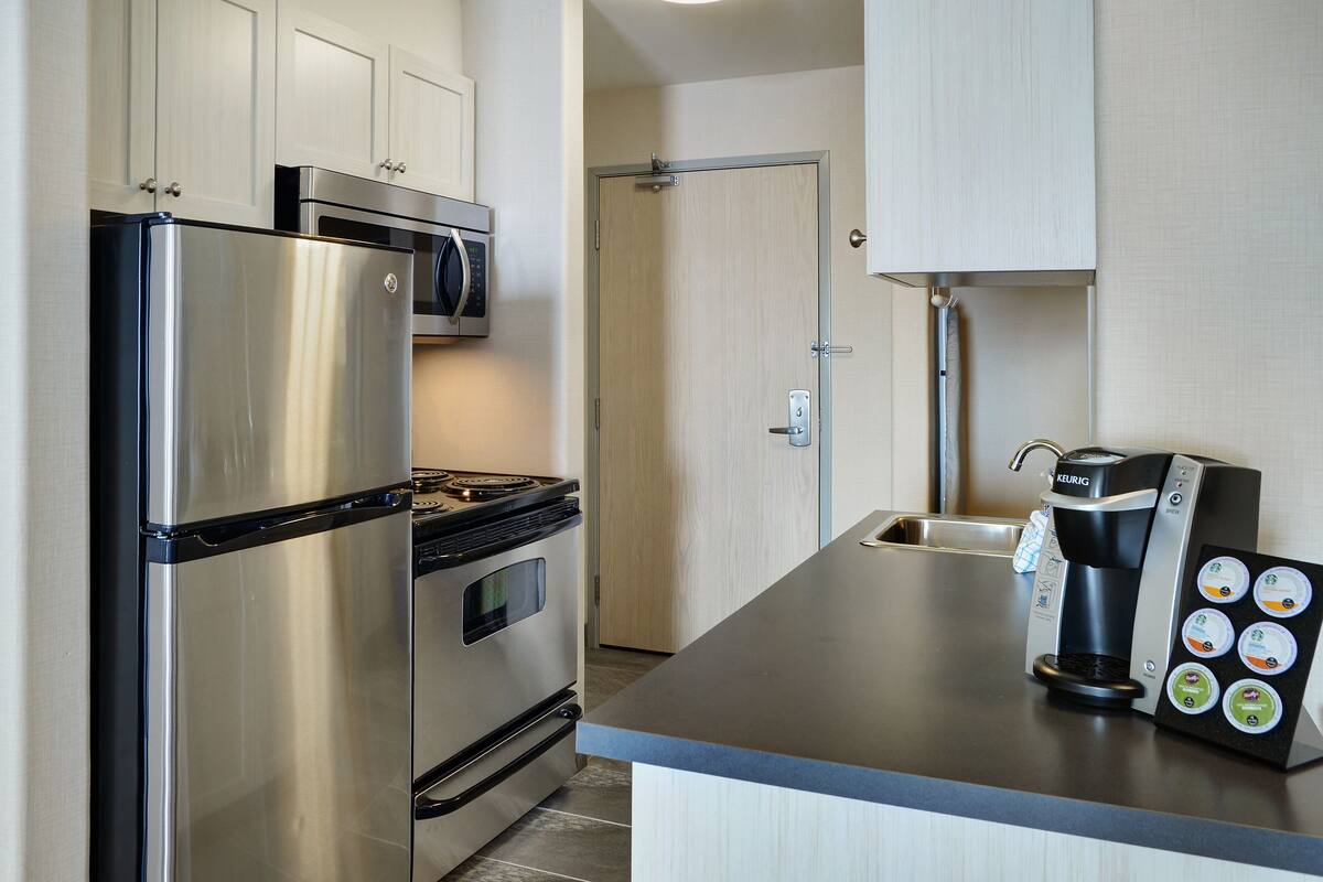 A modern kitchen with stainless steel appliances, a coffee maker, and a built-in microwave.