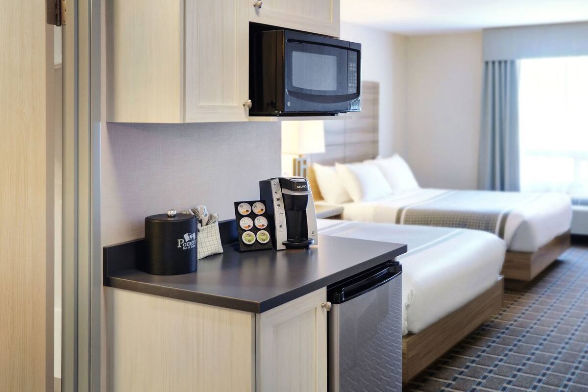 A hotel room with a kitchenette, a microwave, a coffee maker, and a bed with a view.