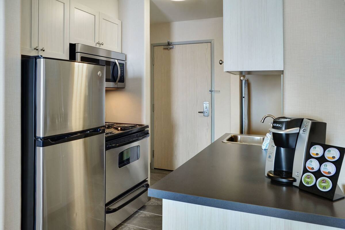 A modern kitchen with stainless steel appliances, a coffee maker, and a kettle.