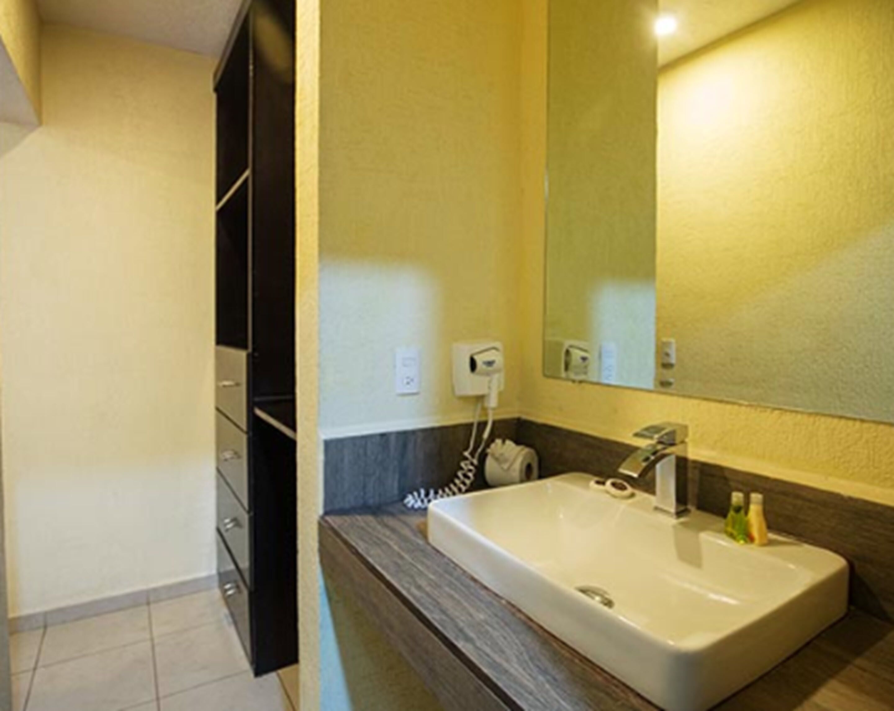 A bathroom with a large sink, a mirror, and a towel rack.