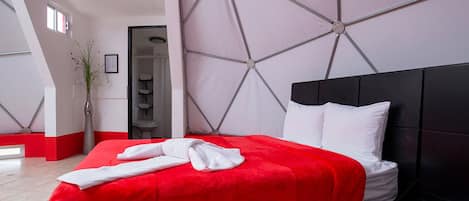 A modern hotel room with a red bedspread, white pillows, and a black headboard.