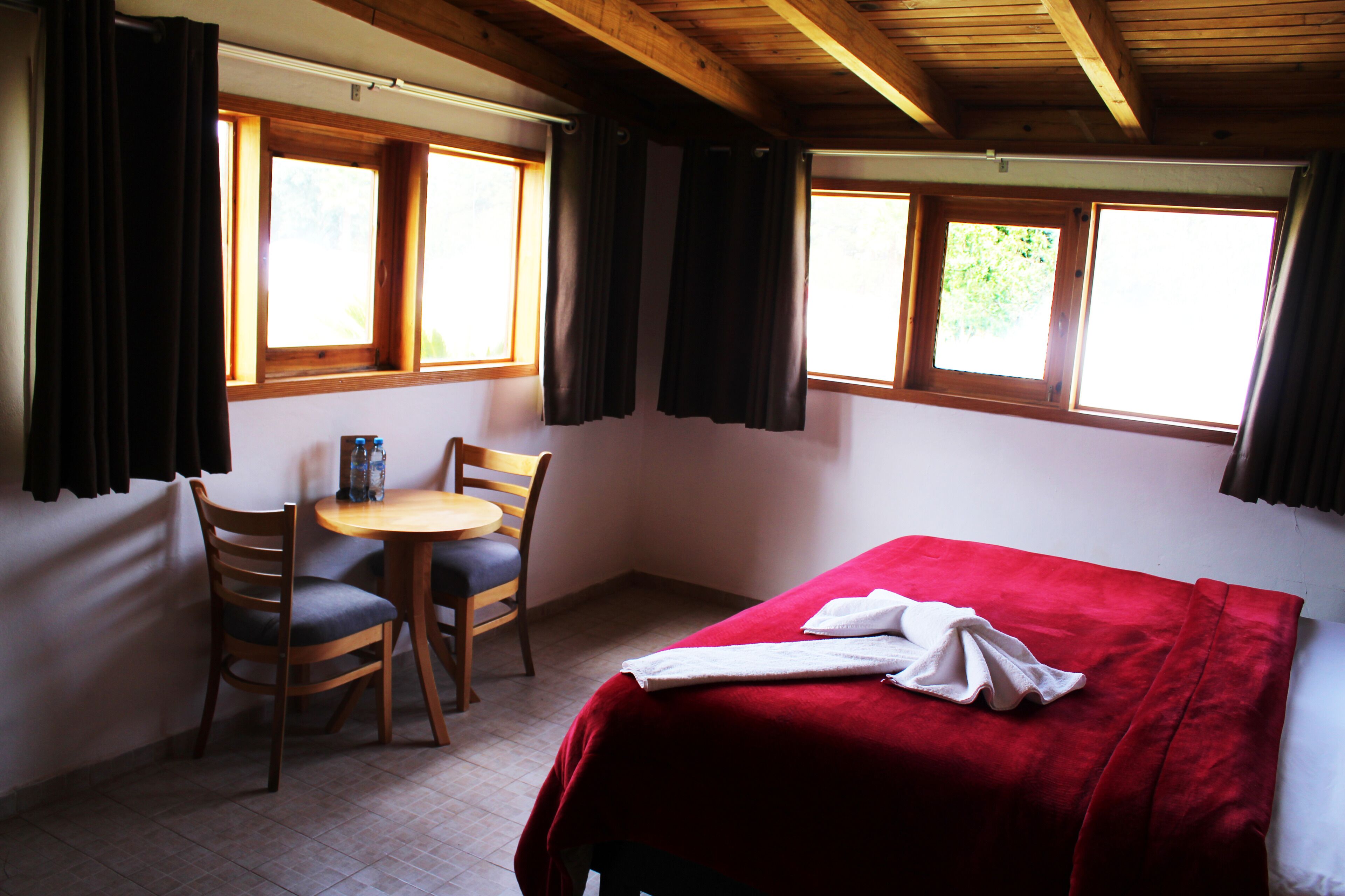 A room with a bed, a table, and two chairs.