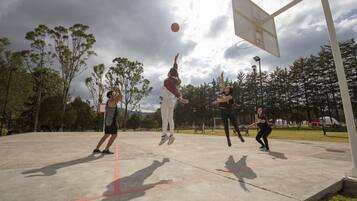 An outdoor basketball court with trees in the background.