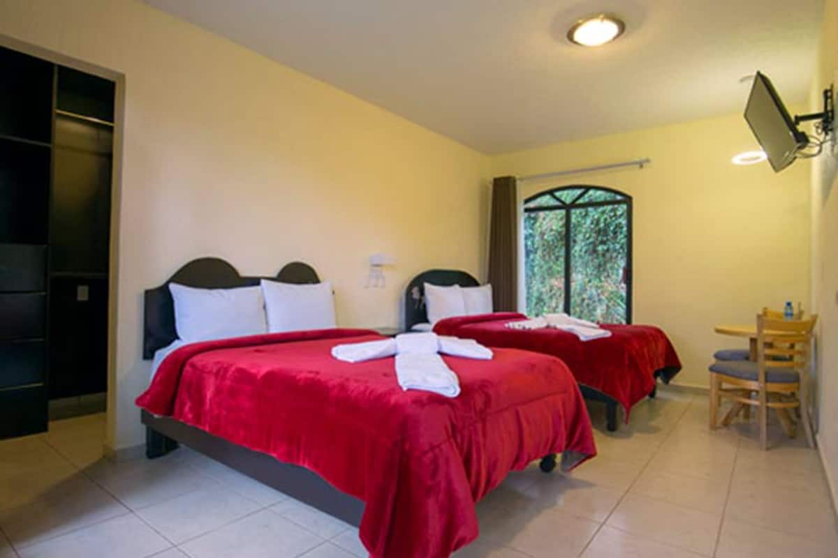 A hotel room with two beds, a desk, and a chair.